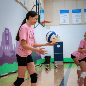 Player smiling and serving Boys & Girls Clubs of Whatcom County kid holding mit