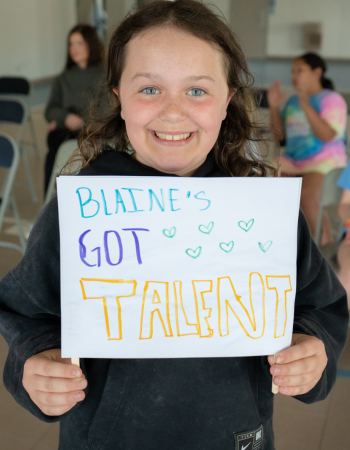 Untitled design (8) Blaine Club member holds a colorful sign that reads, "Blaine's Got Talent"