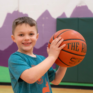 Kid holding basketball A boy smiles and holds a basketball